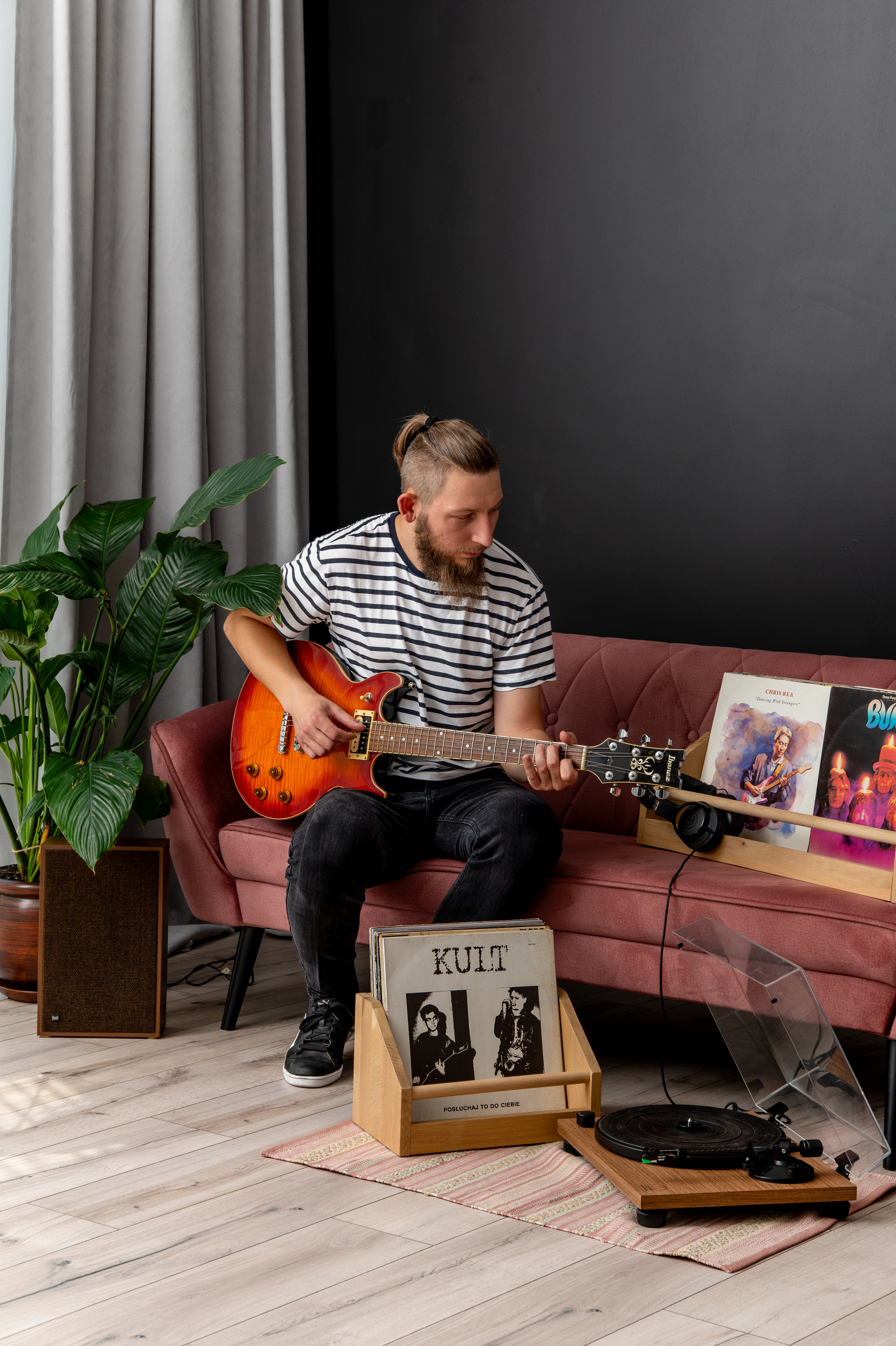 Krystian z gitarą w otoczeniu muzyki i płyt winylowych
